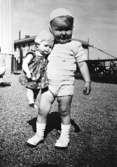 Ett litet barn som håller en docka vid Krokslätts daghem under Margit Emilssons (gift Wannerberg -52) praktik som biträde
1945-10-01 - 1946-08-01.