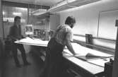 Två män i arbete.
Bilden ingår i serie från produktion och interiör på pappersindustrin Papyrus, 1980-tal.