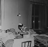 En sköterska tar hand om en patient på Sabbatsbergs sjukhus i Stockholm, cirka 1958. Det var viktigt att ha uppkavlade ärmar vid beröring av patient.