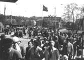 Publik inför Kung Gustav VI Adolfs (1882 - 1973) besök, som inviger och firar Gunnebo slott den 16 maj 1952 i Mölndals centrum. I bakgrunden ses järnvägsövergången på Kvarnbygatan i Mölndalsbro.