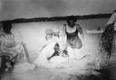 Badklädda kvinnor som tvättar kläder, troligtvis i Tulebosjön cirka 1930.