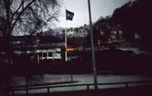 Vy norrut på huvudentrén till Domus barack vid Nya Torget i Mölndal, 1970-tal. I fonden till höger ses närmast (bakom dungen) Missionskyrkan samt villor i området Trädgården.
