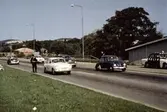 Poliskontroll på Kungsbackavägen i Mölndal, då vi fortfarande hade vänstertrafik, cirka 1965 - 1966. Högertrafik infördes september 1967. I bakgrunden ses Störtfjället och lägenheter på Delbanco- och Lövgatan.
