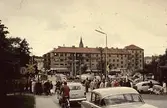 Vid järnvägsövergången i Mölndals centrum, 1960-tal. Järnvägsbommarna över Kvarnbygatan var ofta nedfällda. Dels gick många tåg på Västkustbanan, dels växlade man vagnar och körde in dem på Papyrus industriområde. Kvarnbygatans viadukt Mölndalsbro var färdig 1975, då försvann bommarna och bil- och gångtrafikanter behöver inte längre vänta för att ta sig till centrala Mölndal.