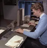 Arbete vid Adrema maskin. Tryckning av kontobeteckning på
kontoutdrag (komplettering av blanketter som förbrukats föregående
dag). Bildmaterial till diaserien 