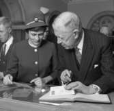Jubileumshedersgäst var dåvarande kung Gustaf VI Adolf. Här skriver
kungen i gästboken och sätter sin namnteckning på ett museibrevkort,
under överinseende av postvärdinnan Inger Svärd.