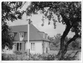 Biskopsgården i Skara
Exteriör dagtid. Del av husets långsida samt gavel mot trädgården, i förgrunden gräsmatta, flaggstång och träd.