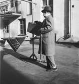 Ervacoreklam för herrkläder
Man med hatt, rock och resväska vid en piskställning på en bakgård
Exteriör