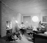 Vardagsrum med eldstad
Lekande barn på golvet, läsande föräldrar