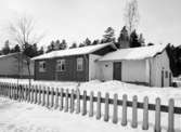 Standardhus, Hultsfred
Exteriör, enplanshus i snölandskap med staket i förgrunden och skogskappa i fonden.