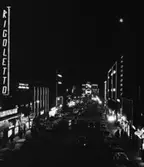 Nattbild, Kungsgatan
Exteriör, Kungsgatan nattetid med lysande lampor och skyltar. I förgrunden upplyst Rigolettoskylt