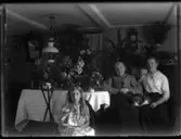 En flicka och två kvinnor vid ett bord med blommor.