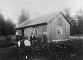 En grupp människor framför en stuga.