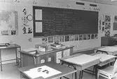 Ett klassrum med bänkar och svarta tavla. Dokumentation av Sagåsens flyktingförläggning, 1992.