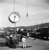 PM 3 Yankeecylindern transporteras till Papyrus fabriksområde via sjön.
Transport av ? av maskindelar.
Några män är med på bilden.