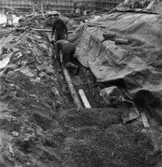 Byggnad N:o 6, tillbyggnad 1954. Läggning av avlopps- och dräneringsrör.
Två okända män