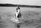 Flicka rider på häst vid en sjö, år 1983. 

