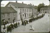 Logen Margareta i demonstrationståg på Stortorget i slutet av 1890-talet. Utanför Kappers raksalong står Kappers dotter Anina, syster till järnhandlare K.J. Wibergs fru, född Olga Kappers. Polisen är konstapel Norén. Vid x går den gamle nykterhetskämpen Hall. Alfr. Jonssons båda hus till vänster.