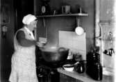 Köksinteriör, matlagning, en äldre kvinna.
Fru Sofia Johansson, mormor.