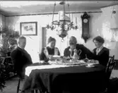 Rumsinteriör, fyra personer vid bordet.
Kaffebjudning.