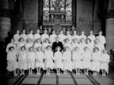 33 konfirmander, 33 flickor och pastor Torsten Holm.
Interiör av Nikolaikyrkan.