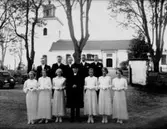 Konfirmander, 6 flickor, 5 pojkar och pastor Thorman.
Tysslinge kyrka i bakgrunden.