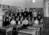 Klassrumsinteriör, 23 skolbarn med lärarinna.