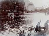 Fyra kvinnor vid klappbryggan vid Svartån, liten ångslup i ån, Slottet i bakgrunden.