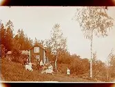 Sommarstugan Fridensborg, envånings sommarstuga med inredd vind och veranda. Fem barn och två vuxna framför stugan, 2 getter.
Fotograf Sam Lindskog