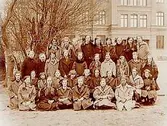 Västra skolan, 35 skolflickor med lärare, sal 22.
Skolbyggnad i bakgrunden.
Fröken Jenny Karlsson