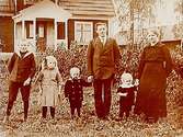 Envånings bostadshus med frontespis.Familjegrupp 6 personer framför huset.K.G. Karlsson