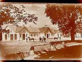Stallbyggnad med fyra hästar och tre karlar.
A.G. Andersson