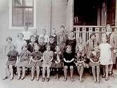 Rynninge folkskola, 23 skolbarn med lärare fröken A. Dahlén.
Skolbyggnad i bakgrunden.