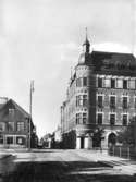 Stenhus i tre och fyra våningar med livfull tornprydnad, K.F.U.M. huset.
Storgatan mot söder från Järnvägsgatan.
Bilden är troligen en reproduktion (1934) efter en bild från ca 1903, tagen av fotograf Axel Barr.