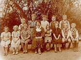 Rynninge skola, 12 skolbarn med lärarinna fru Andersson.Skolbyggnad i bakgrunden.