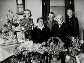 Stationskarl Algot Johanssons fru på 50 årsdagen.Rumsinteriör, familjegrupp fem personer.