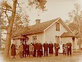 Envånings bostadshus med inredd vind och förstebro. Grupp 14 personer framför huset.
Eskil Anderssons 50 årsdag.