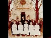 Rinkaby kyrka i bakgrunden.
Glanshammars konfirmander, 5 flickor, 5 pojkar och kyrkoherde Johansson.