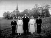 4 konfirmander, 2 flickor, 2 pojkar och pastor Sven Ljunggren.
Hovsta kyrka i bakgrunden.