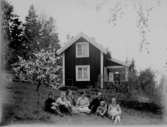 Familjegrupp 7 personer.
Sommarstugan i bakgrunden.
Fotograf Sam Lindkogs med familjen Hulda, Märta, Margit, Ingrid, Sven och Karl-Erik.