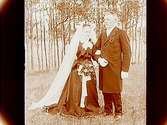 Brudpar, bruden i svart klänning, vit slöja, krona, brudgummen i frack.
John Carlsson