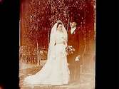 Brudpar, bruden helt i vitt, med slöja och krona, brudgummen i frack och hög hatt.
Elsie Johansson