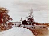 Ekeby kyrka i bakgrunden.
Landsväg, betande kor.
(Reproduktion efter en bild 18x24 cm).