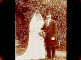 Brudpar, bruden i vit klänning, slöja och krona, brudgummen i frack och hög hatt.
Emil Gustafsson