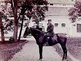 En man till häst.Bostadshus i bakgrunden.G. Börjesson