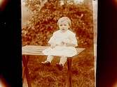 En liten flicka på trädgårdsbordet.
A.G. Södervall