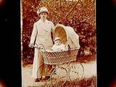 En kvinna med ett barn i barnvagn.
Alma Nyberg