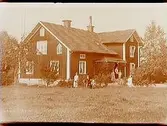 En och en halvvånings bostadshus med förstubro. Grupp 7 personer framför huset.
Anders Nilsson