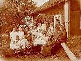 Envånings knuttimrad bostadshus med förstebro.
Släktgrupp på Kristinadagen, 20 personer utanför stugan.
Fru Klara Sjöberg
Bilden föreställer Clara Sjöberg (hon stavade själv med 