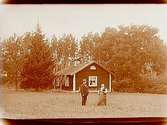 Envånings bostadshus, äldre kvinna och man framför huset.
Karl Viktor Andersson